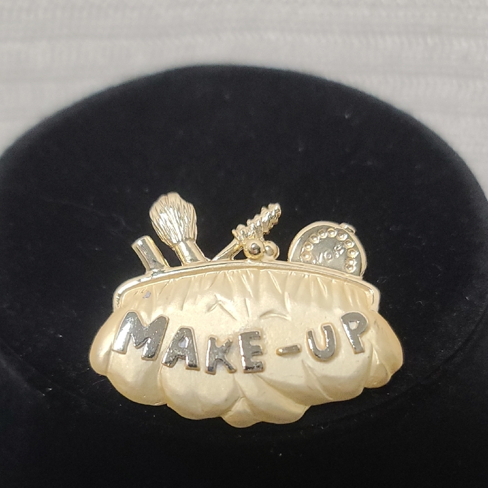 Vintage gold tone brooch with makeup design. EUC
